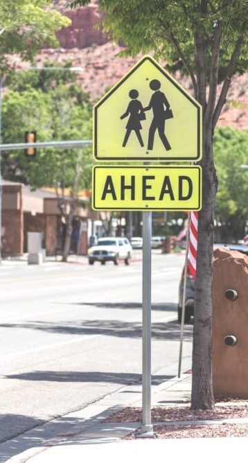 personal injury attorney at chain law will help with any pedestrian accidents, Crosswalk Sign Against green trees in small town