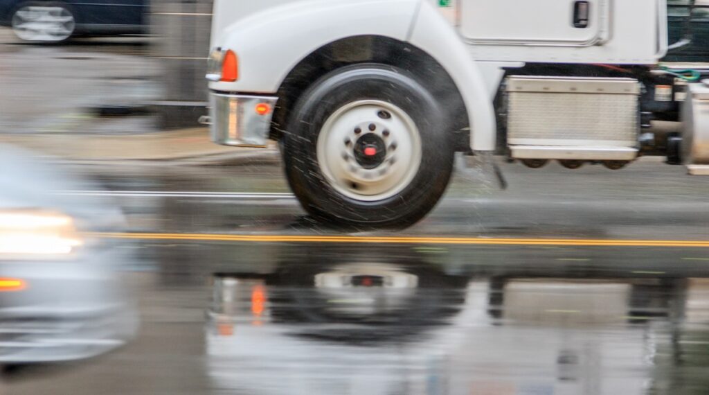 kern county truck accident lawyers, rainy day a truck passes a car at fast speeds in a rainstorm